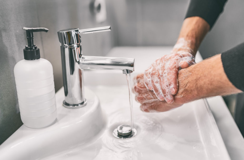 Close-up of a person washing their hands in a bathroom sink.