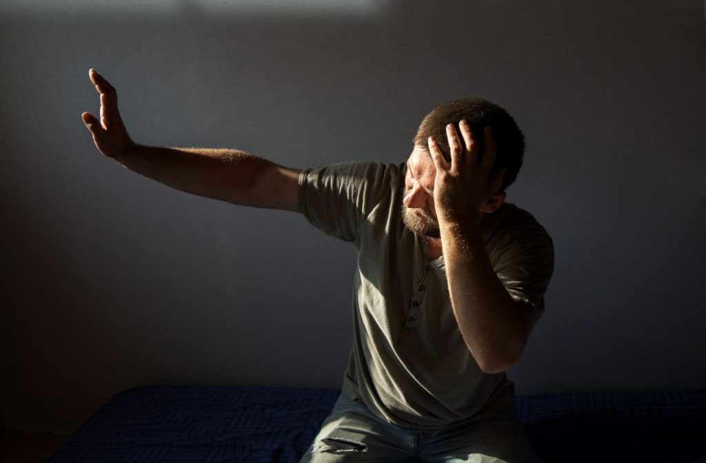 A man blinded by the lights trying to block out sunlight using his hand.