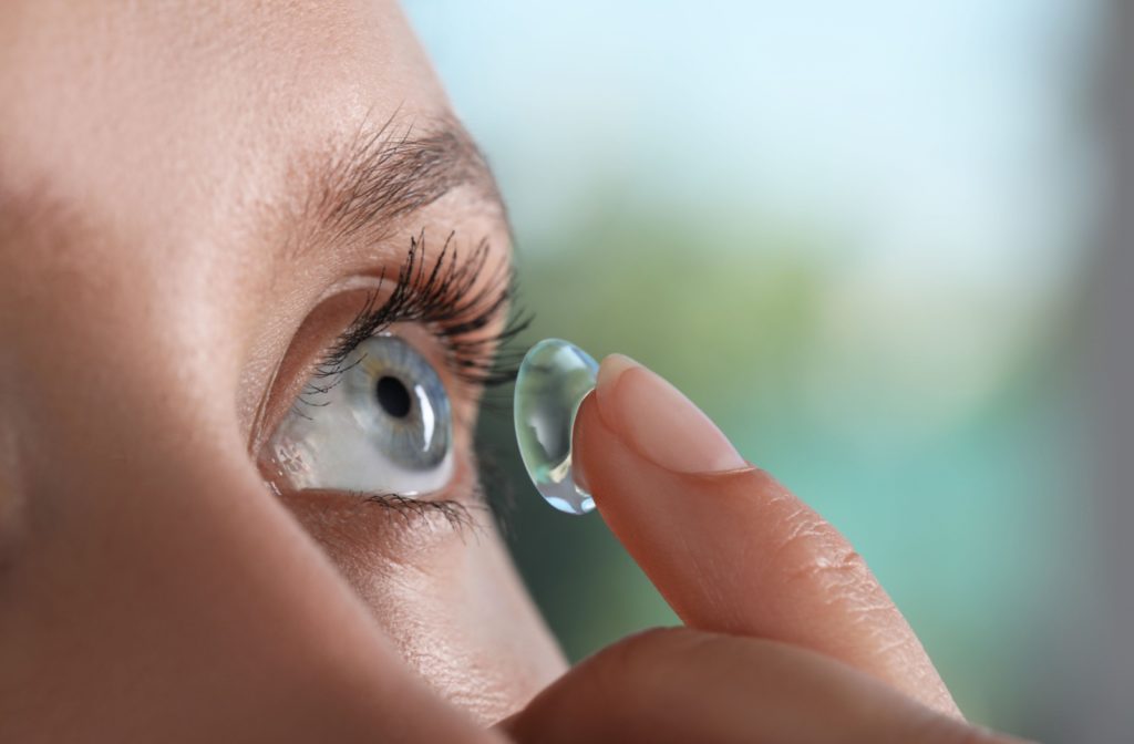 Young woman carefully inserting a contact lens in her eye.