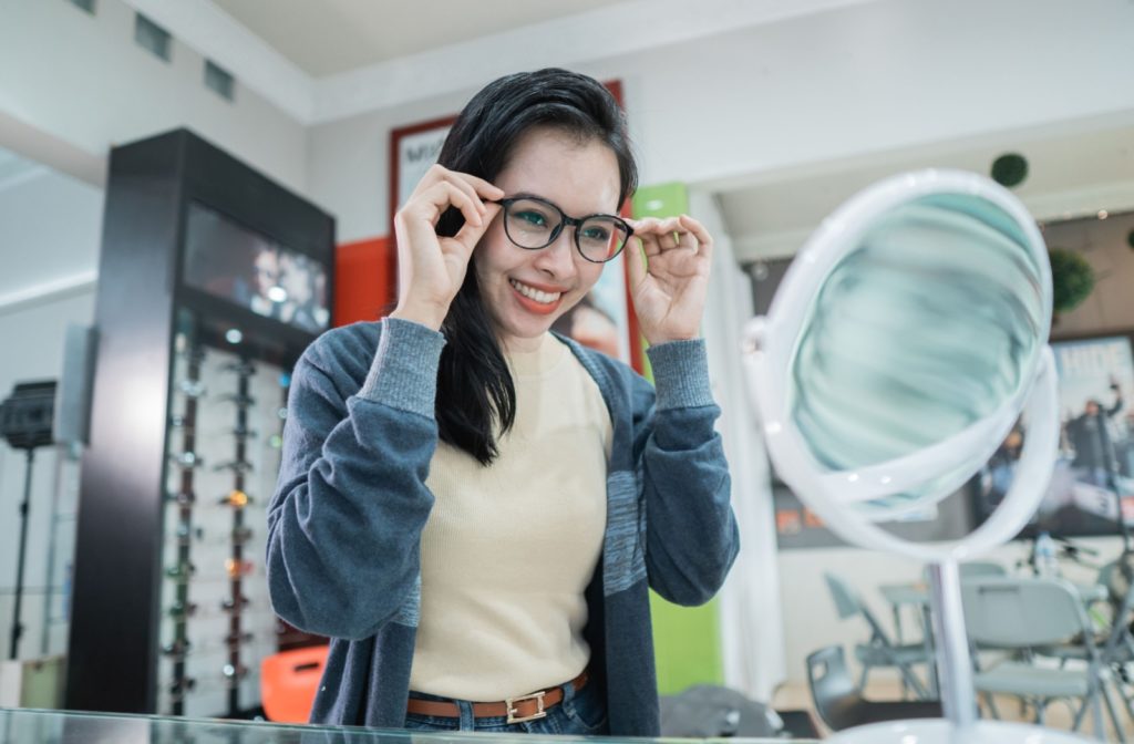 A person tries on a new pair of glasses at their optometrist.