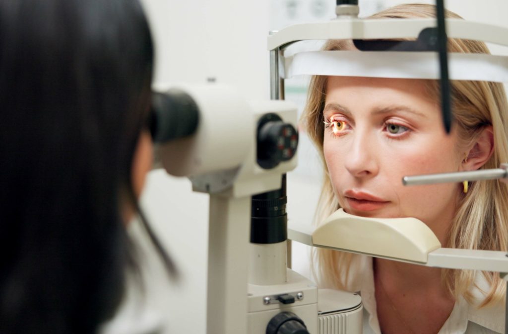 An optometrist examining a patient's eyes with a slit lamp during their annual contact lens exam.