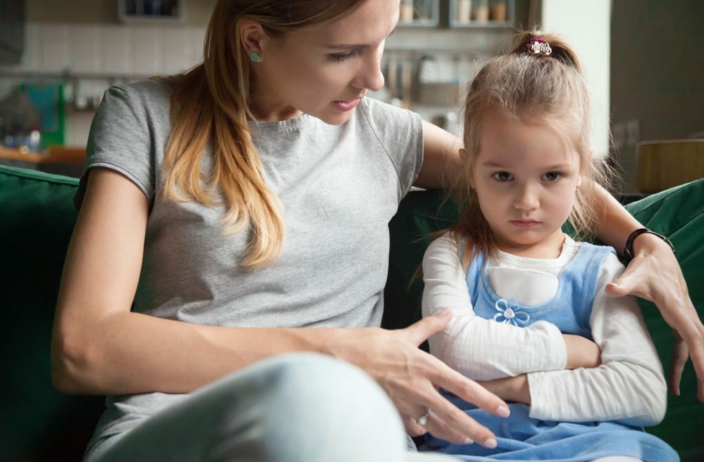 With an arm around their upset child, a parent explains the importance of taking eye drops, attempting to reassure them