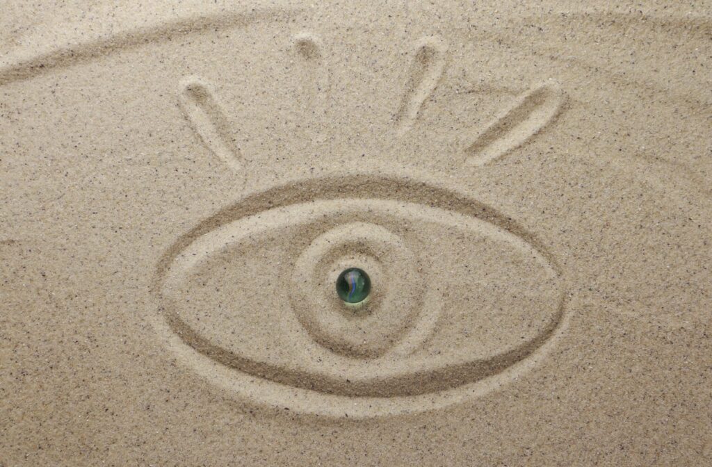 A human eye drawn in the sand.