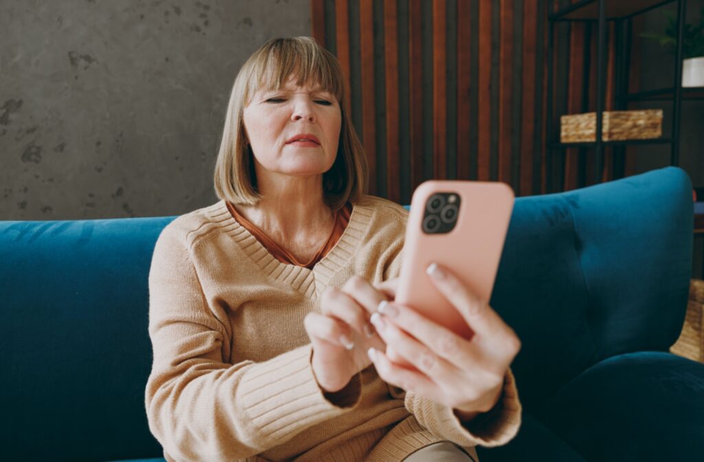 A person holding their phone out, squinting to try and read what is on the screen.