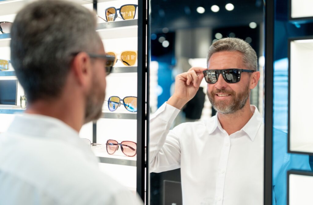 A person looking into a mirror at their optometrist's office while trying on a new pair of sunglasses.